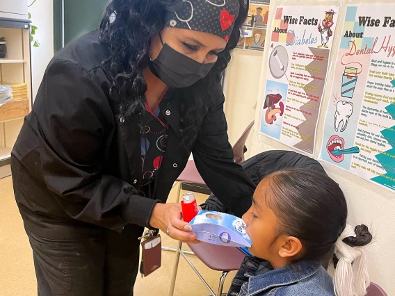 Chinle nurse student using an inhaler on a female child