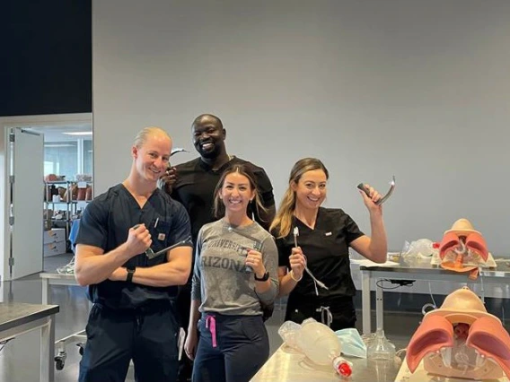 four RISE students smiling and posing in a lab, surrounded by equipment