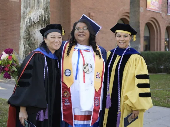 Three Native American students pose for a photo at their graduation ceremony.