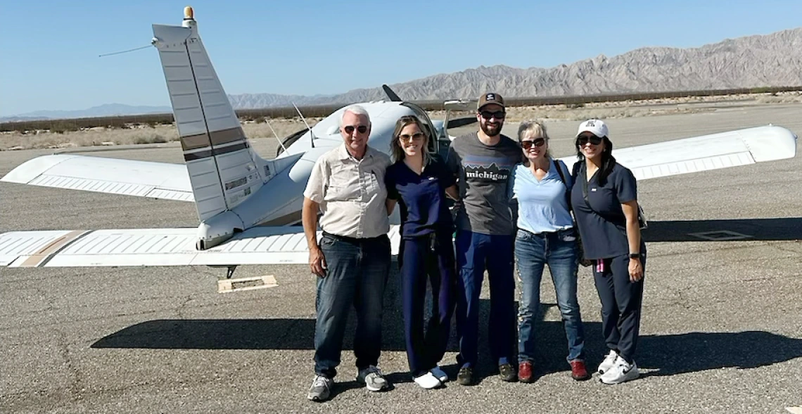 Five people standing in front of air plane