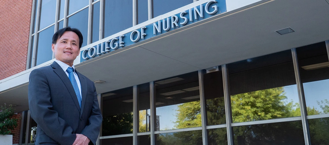 Dean Ahn standing in front of the College of Nursing building entrance.