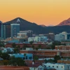 Wide view of the University of Arizona campus with mountains and a sunset in the background.